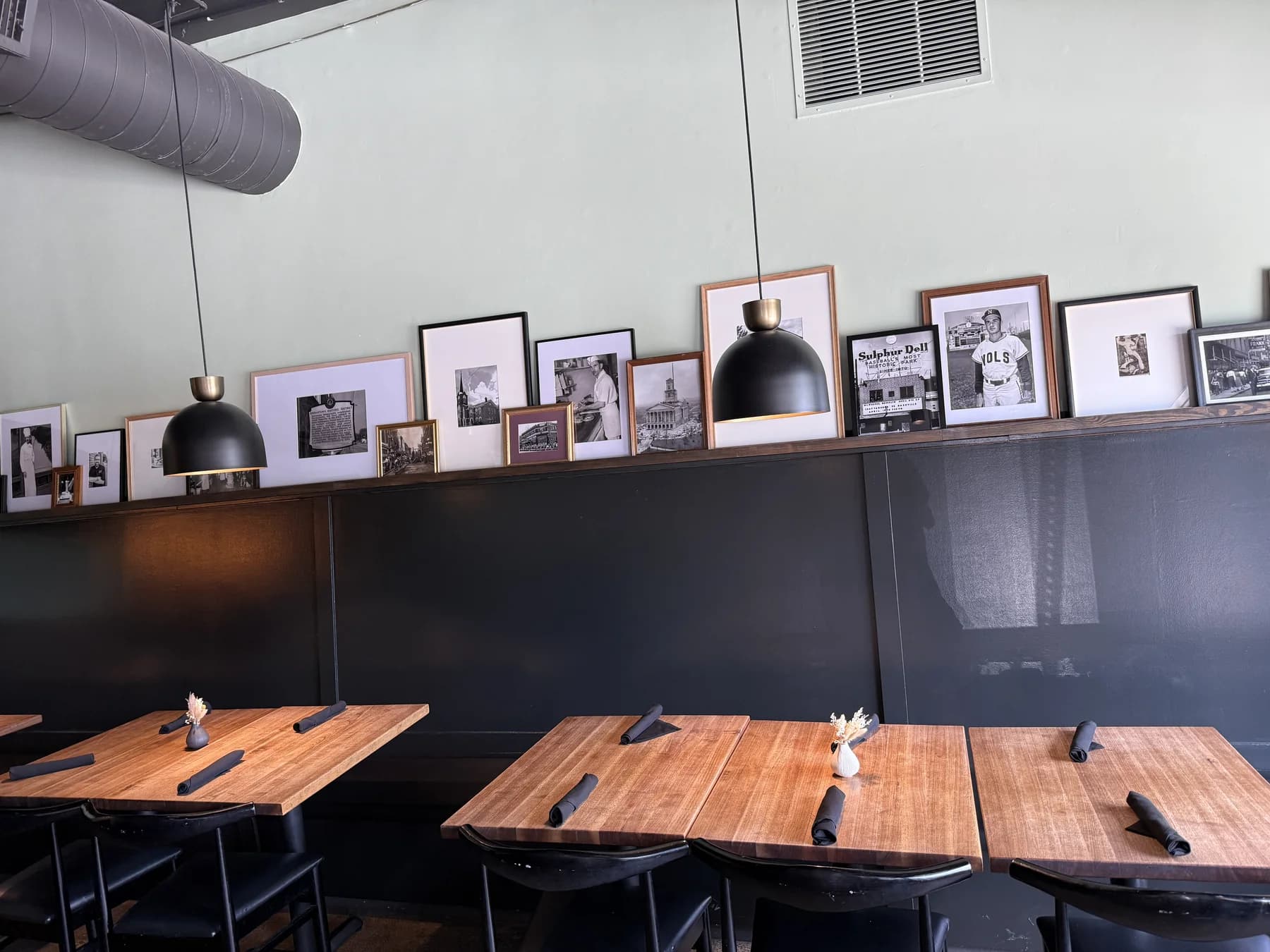 Framed black-and-white community photos displayed along a restaurant wall above dining tables